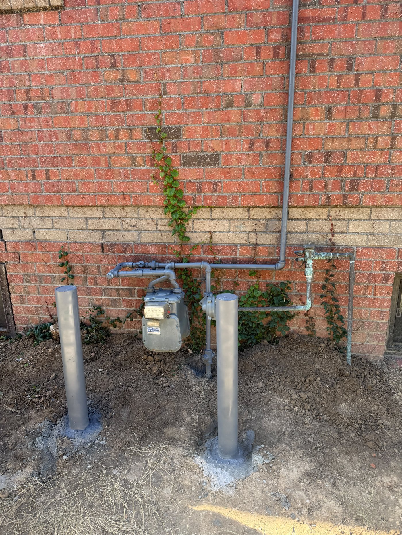 Protective bollards installed around a gas meter.